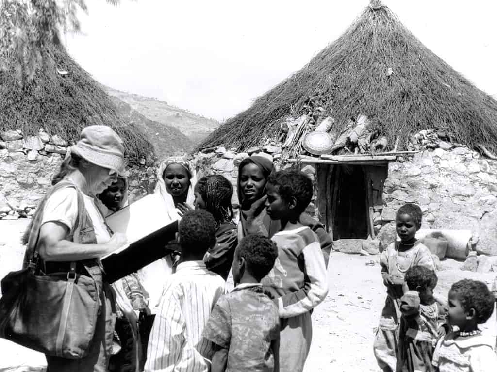 Betty LaDuke sketching amongst children in Eritrea. 1997. Photo courtesy of Betty LaDuke