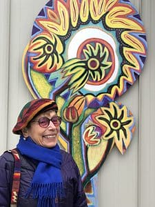 Artist Betty LaDuke in front of one of her paintings.